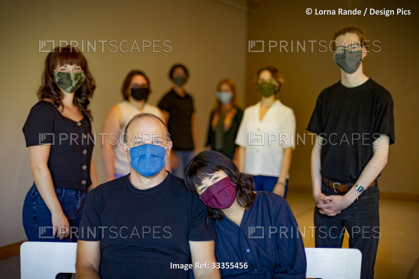 Portrait of a work team wearing face masks and physically distanced in a room; ...