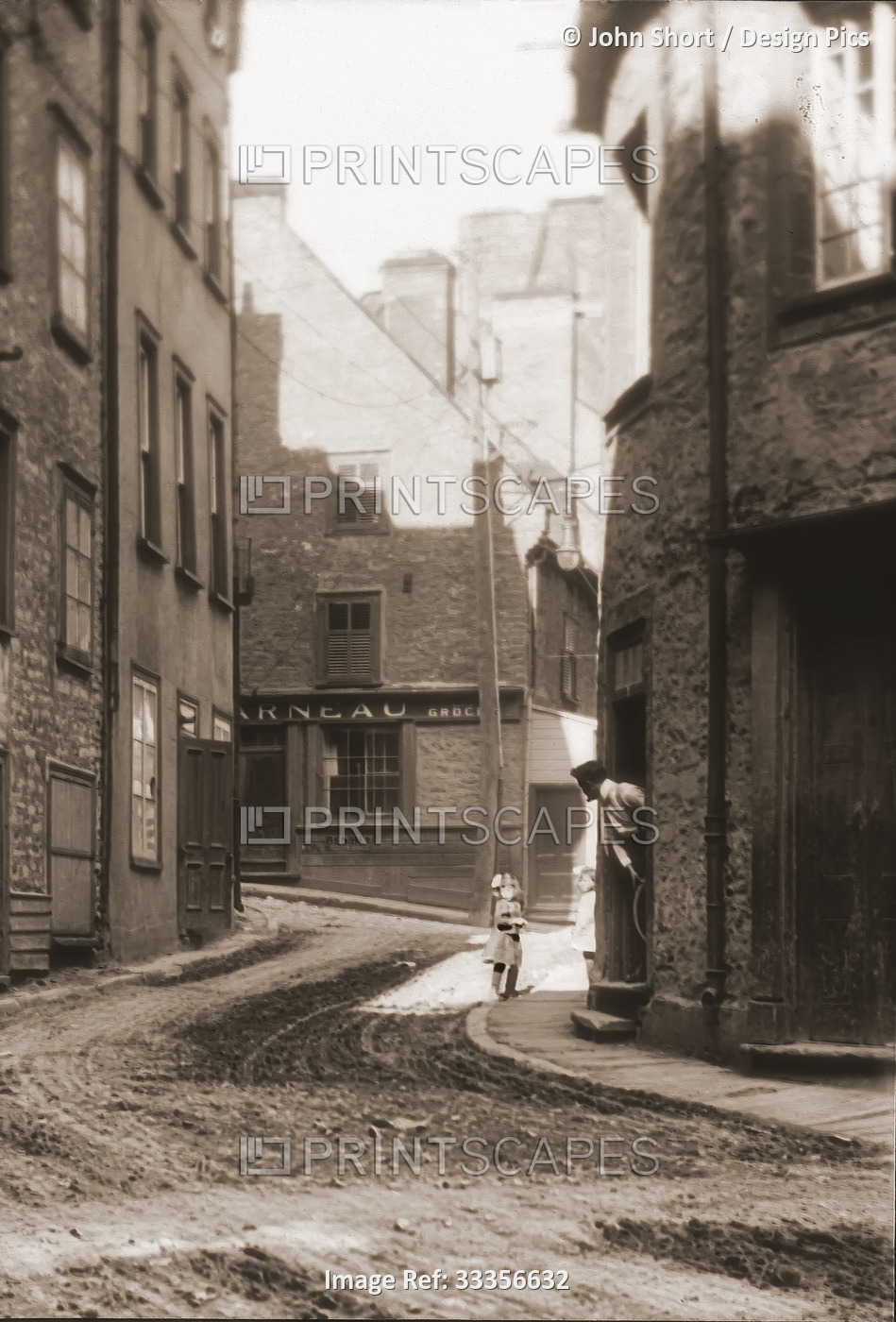 A man stands hanging out of a doorway watching two children with local pub/bar ...