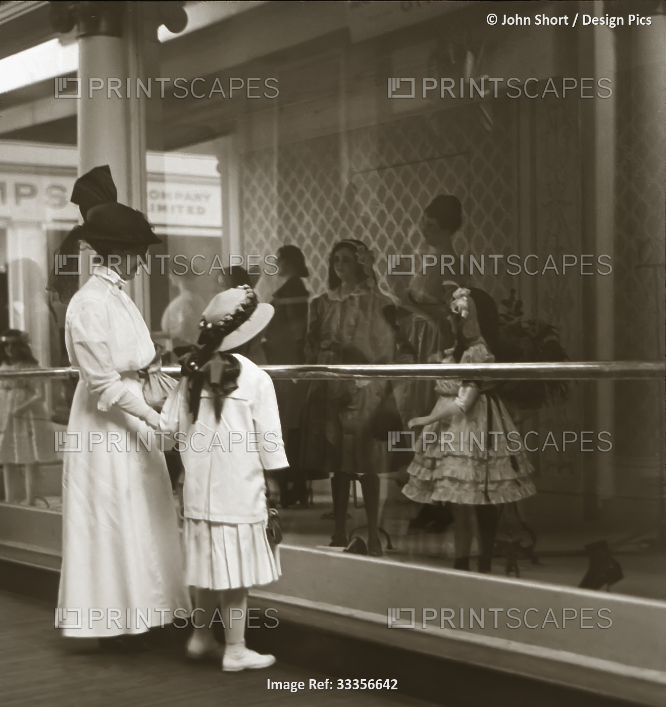 Mother and daughter looking in shop window in Victorian or Edwardian era in ...