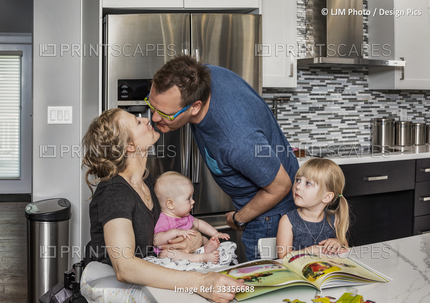 A husband kissing his paraglegic wife while they are reading and making a ...