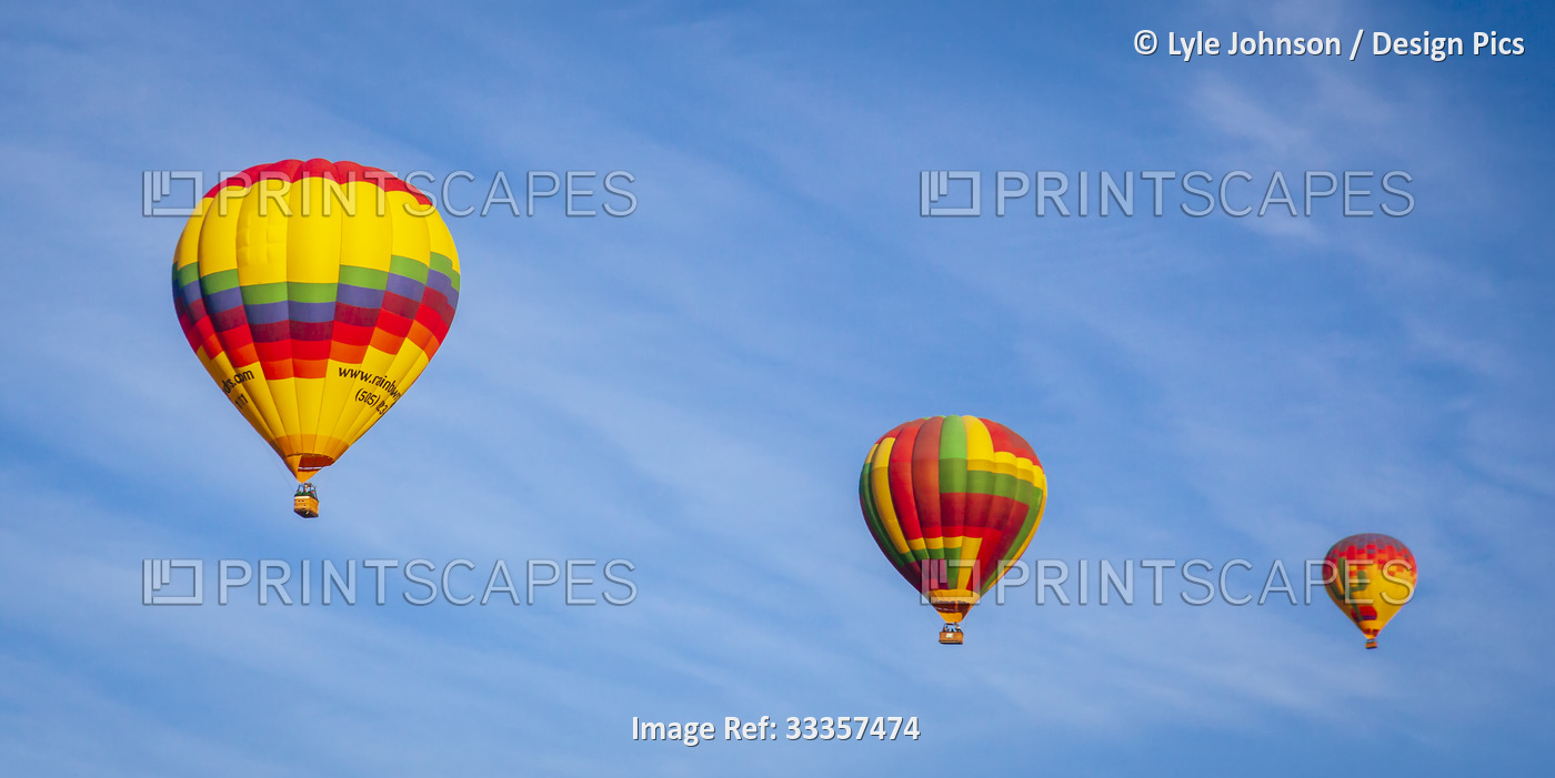 Three vibrant coloured hot-air balloons in the air; Phoenix, Arizona, United ...
