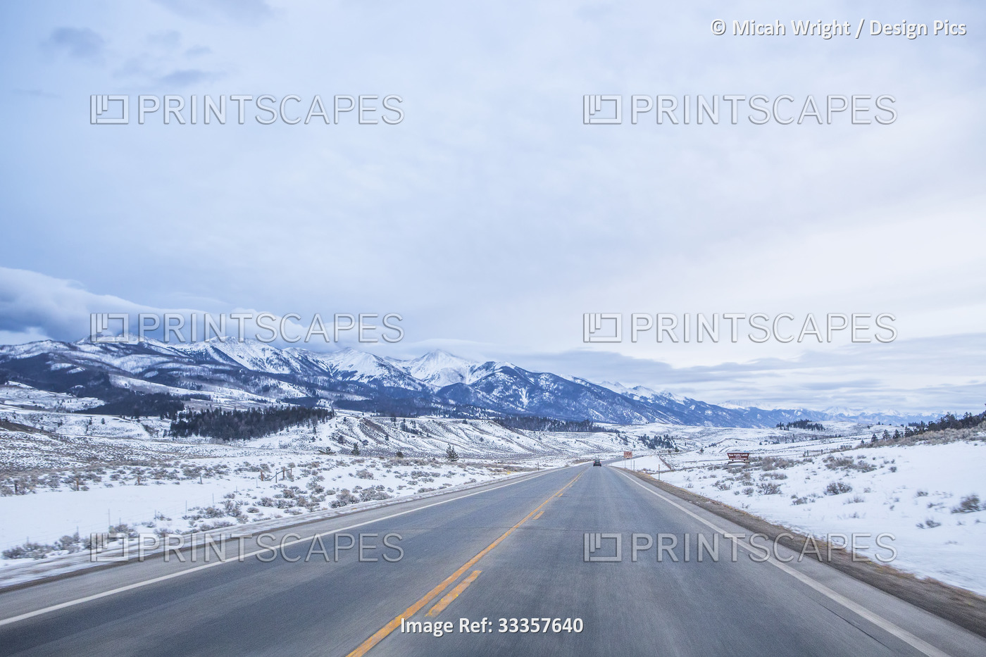 A drive down a snowy, empty highway through southern Colorado on a cloudy day; ...