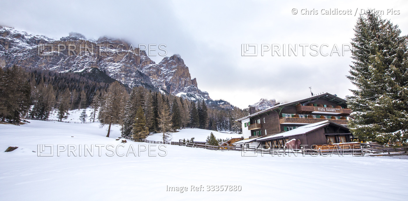 Ciasa Salares Hotel among pine trees and mountains in the snow, in Val Badia, ...
