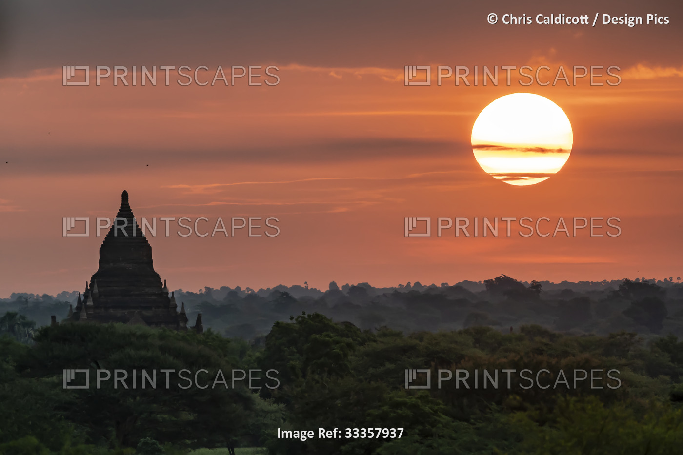 Silhouette of pagoda with the sun rising above the Plain of Bagan at dawn; ...