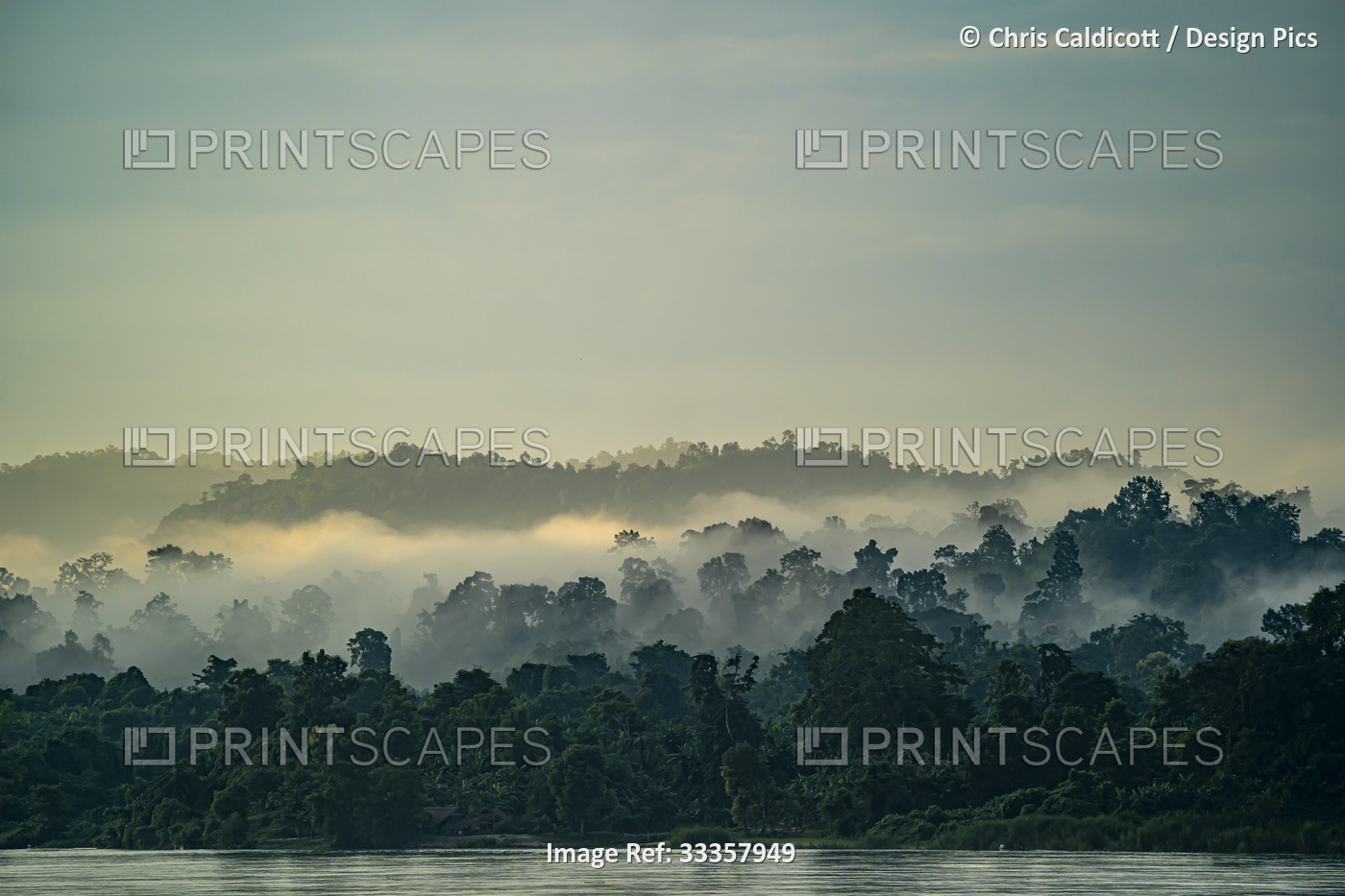 Dawn morning mist rising over the jungle covered banks of the Ayeyarwady ...