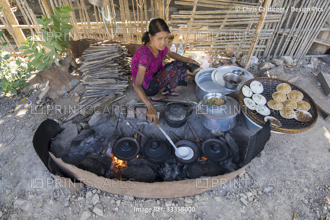 Woman cooking savoury crepes in a rural village along the Irrawaddy River, ...