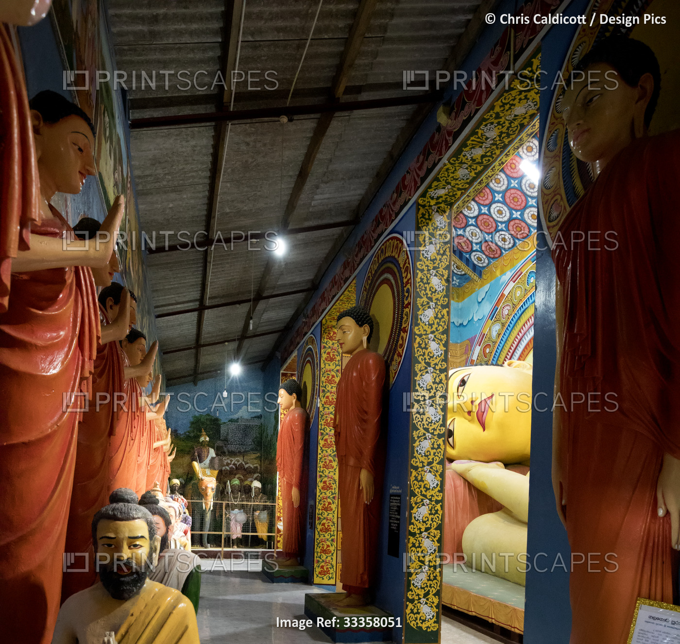 Hallway lined with statues of Standing Buddhas and sculptures of holy men ...