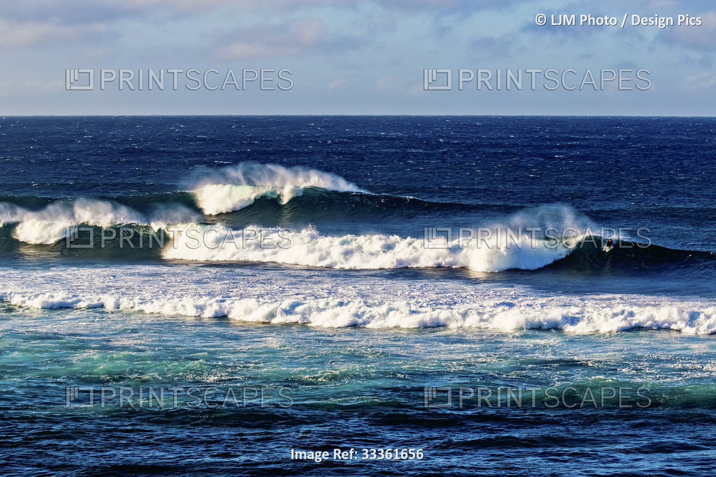 Surfers riding huge waves at Ho'okipa Beach Park near Paia with a blue sky and ...