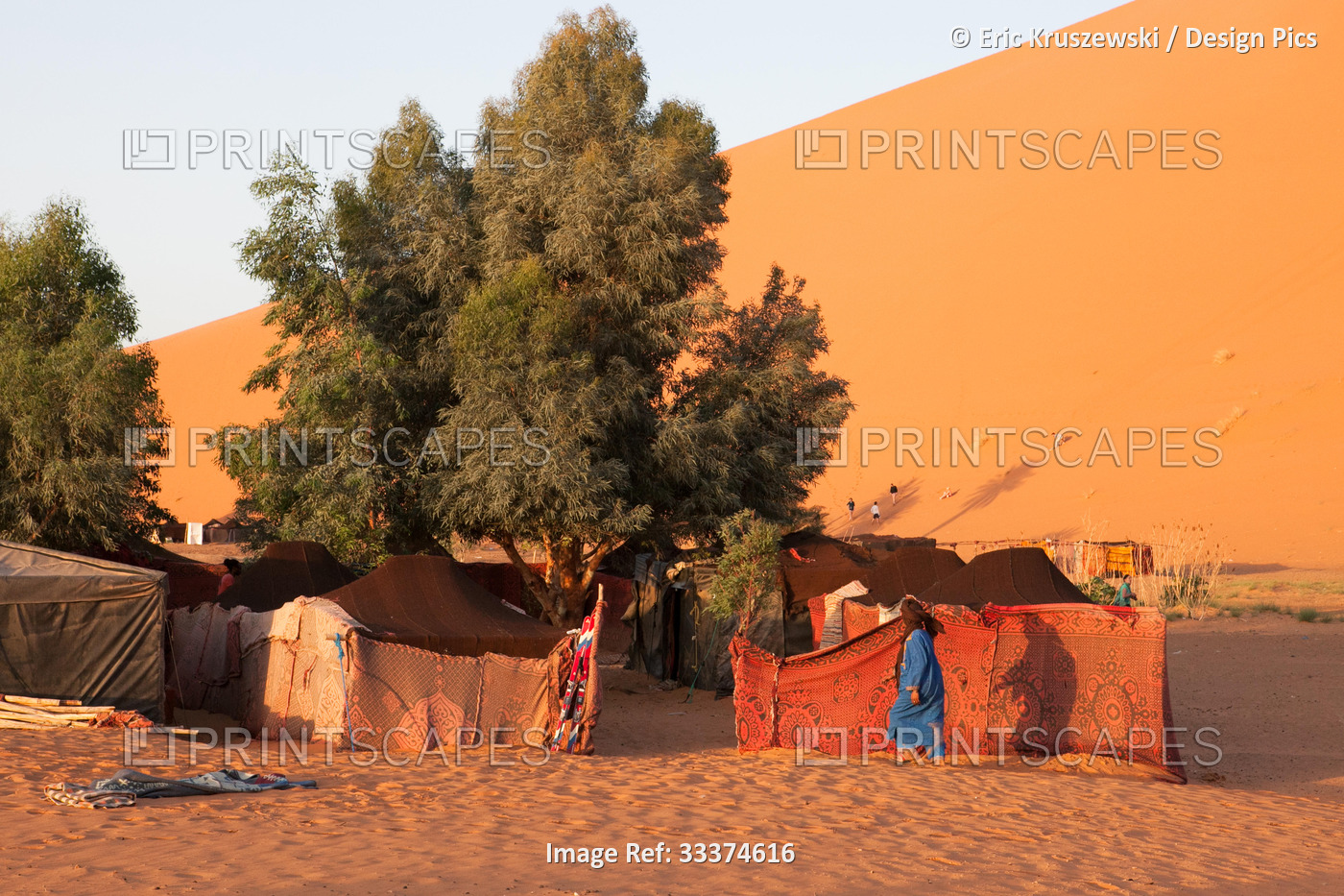 A Moroccan man walks among a tented camp located in the Sahara desert.; Erg ...