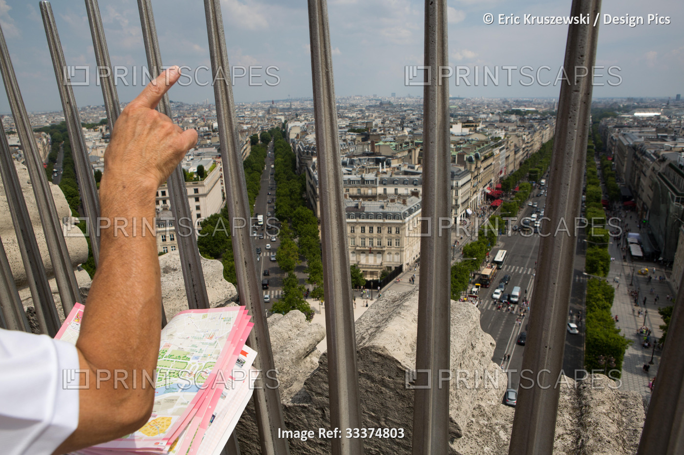 A tourist viewing a map and pointing at the Paris landscape from atop the Arc ...