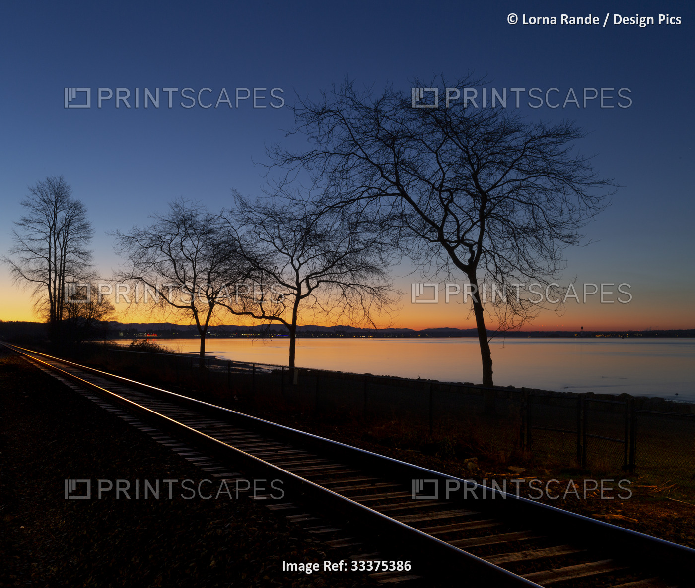 Early morning light illuminates the coast and train tracks running along the ...