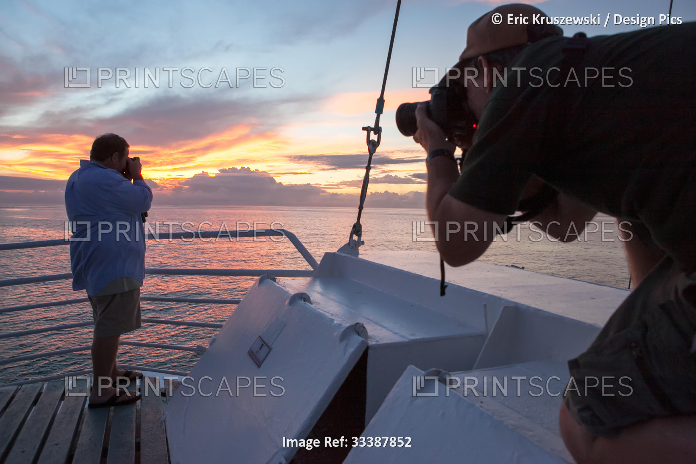 Two passengers on a tourist expedition vessel photographing sunset over the ...