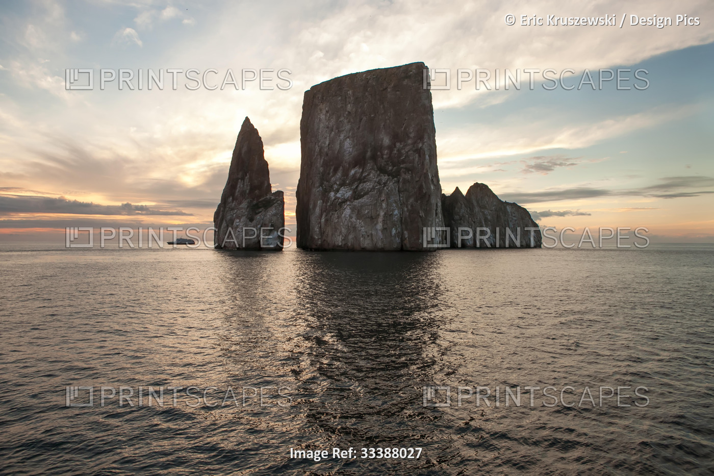 An expedition vessel passes near a large rock formation at sunset.; Pacific ...