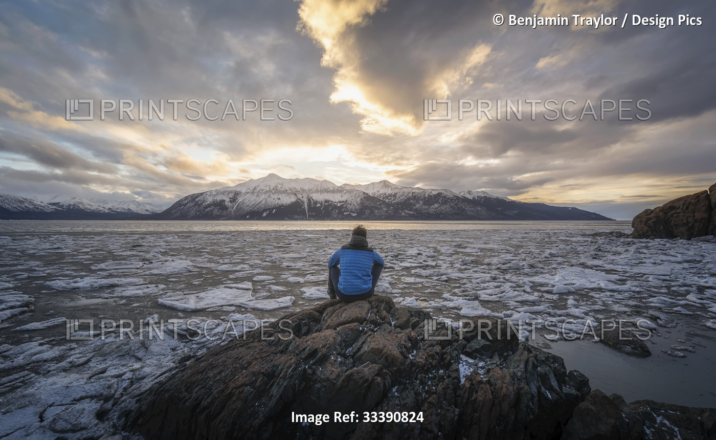 View taken from behind of a man sitting on rocks at the outpost of Beluga Point ...