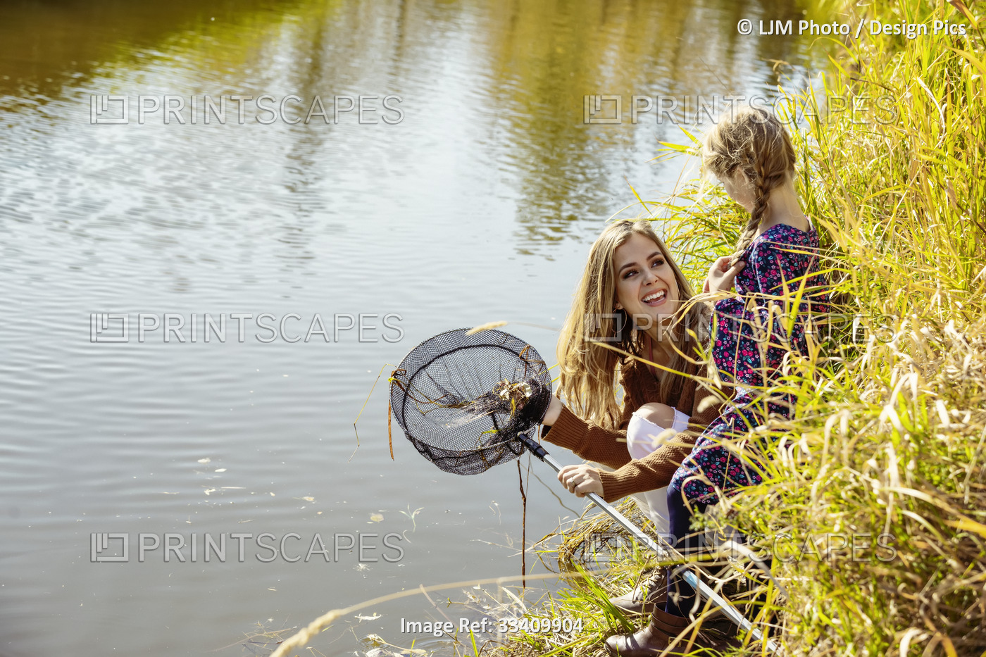 A mother spending quality time outdoors with her daughter and using a net to ...