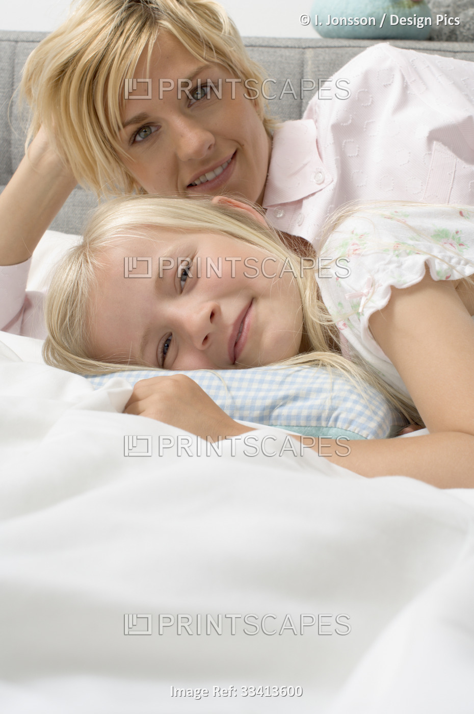 Portrait of a mother and young daughter laying on a bed together; Germany