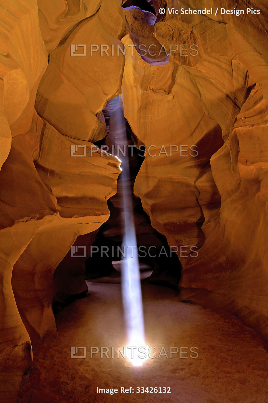 Shaft of light creates a glowing beam in a slot canyon in Antelope Canyon; ...