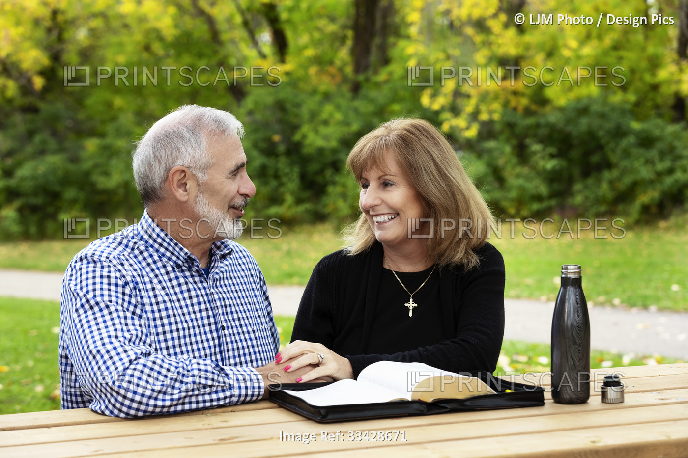 A mature couple sharing devotional time together and studying the bible at a ...