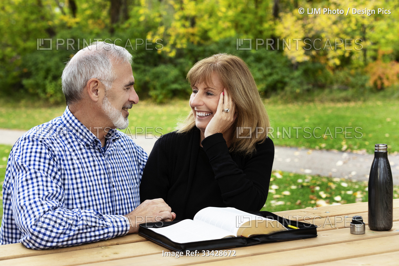 A mature couple sharing devotional time together and studying the bible at a ...