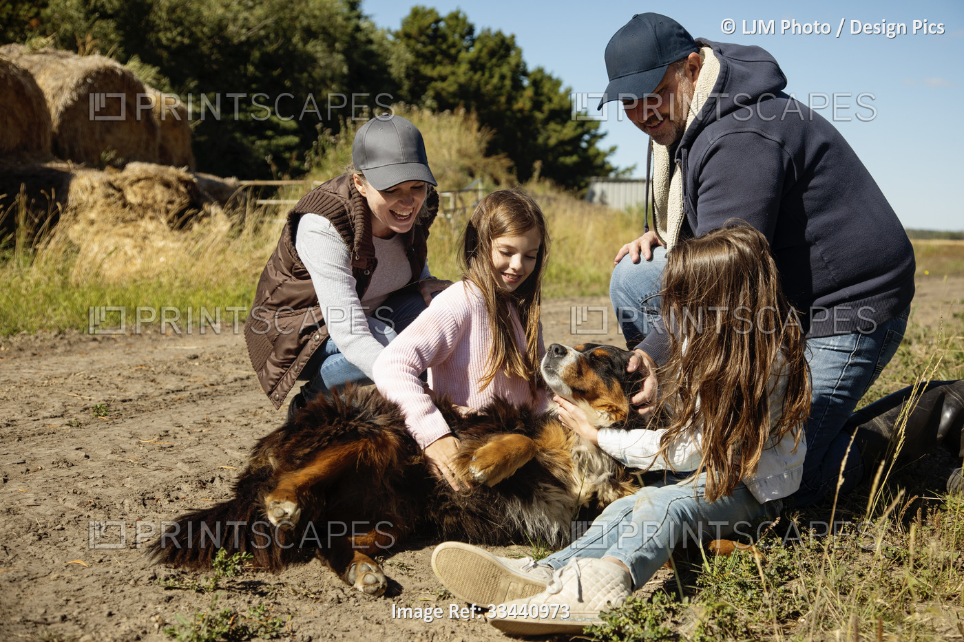 Parents crouching down next to their two young girls that are sitting on the ...