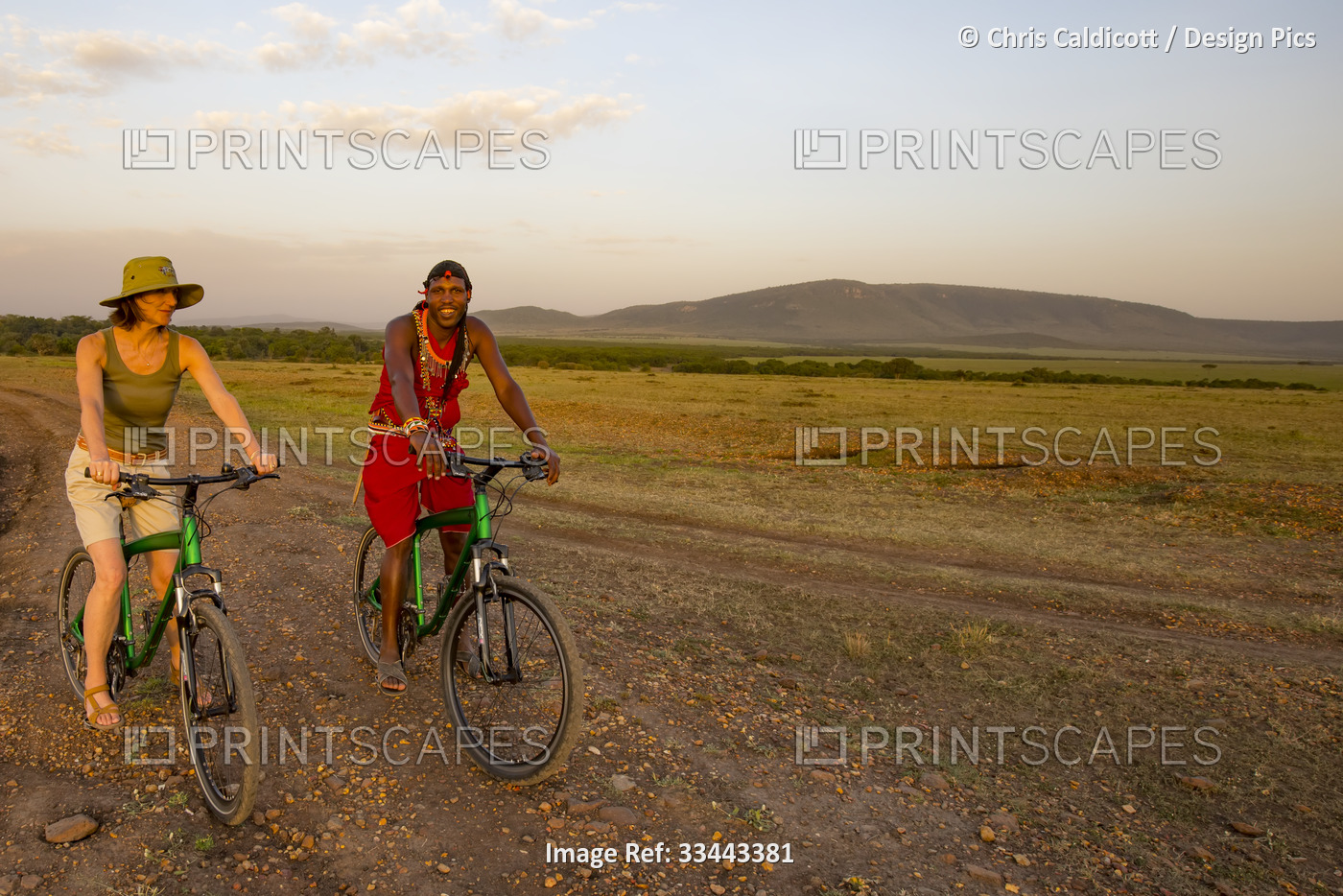 Tourist with guide on mountain bike safari in the Maasai Mara National Reserve, ...