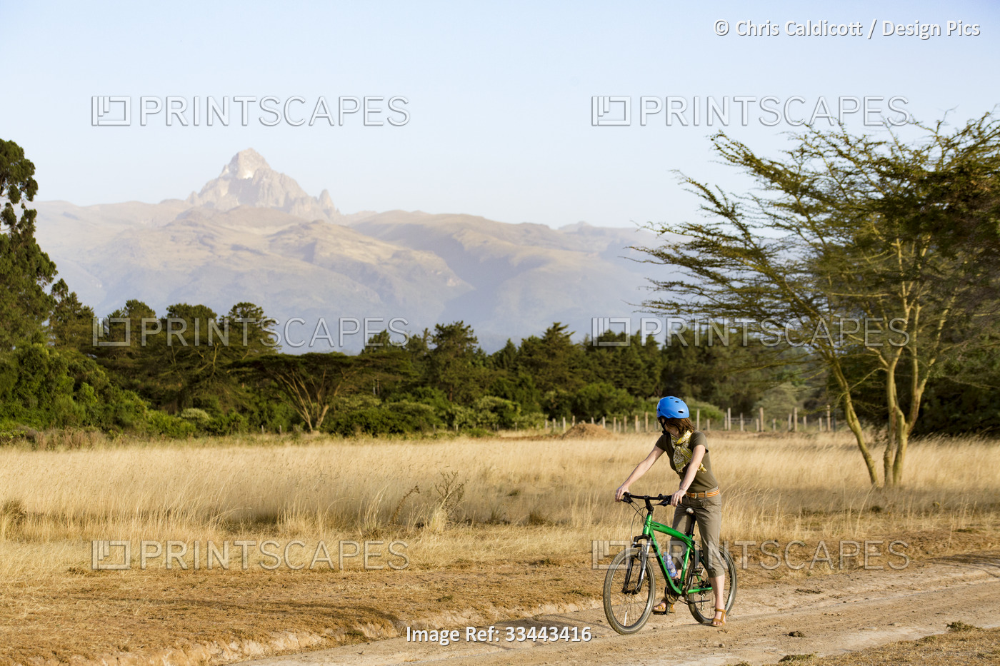 Tourist on mountain bike riding safari in Mount Kenya National Park, looking at ...