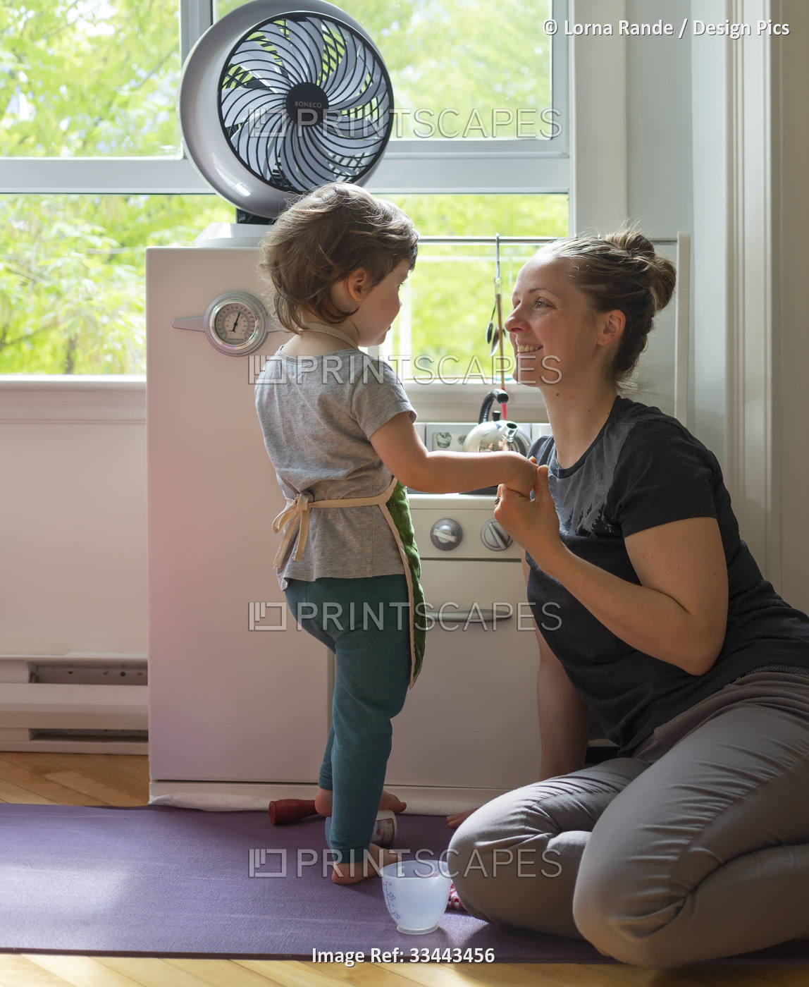 Mother and young daughter play together at home in a toy kitchen; North ...