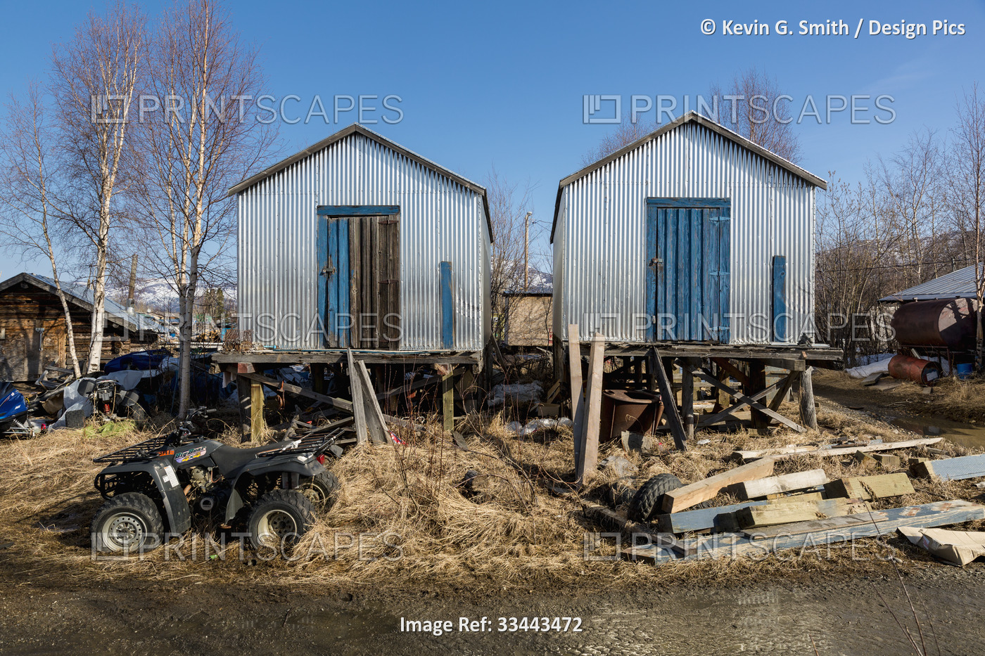 Two corrugated metal storage sheds with weathered blue wooden doors, elevated ...