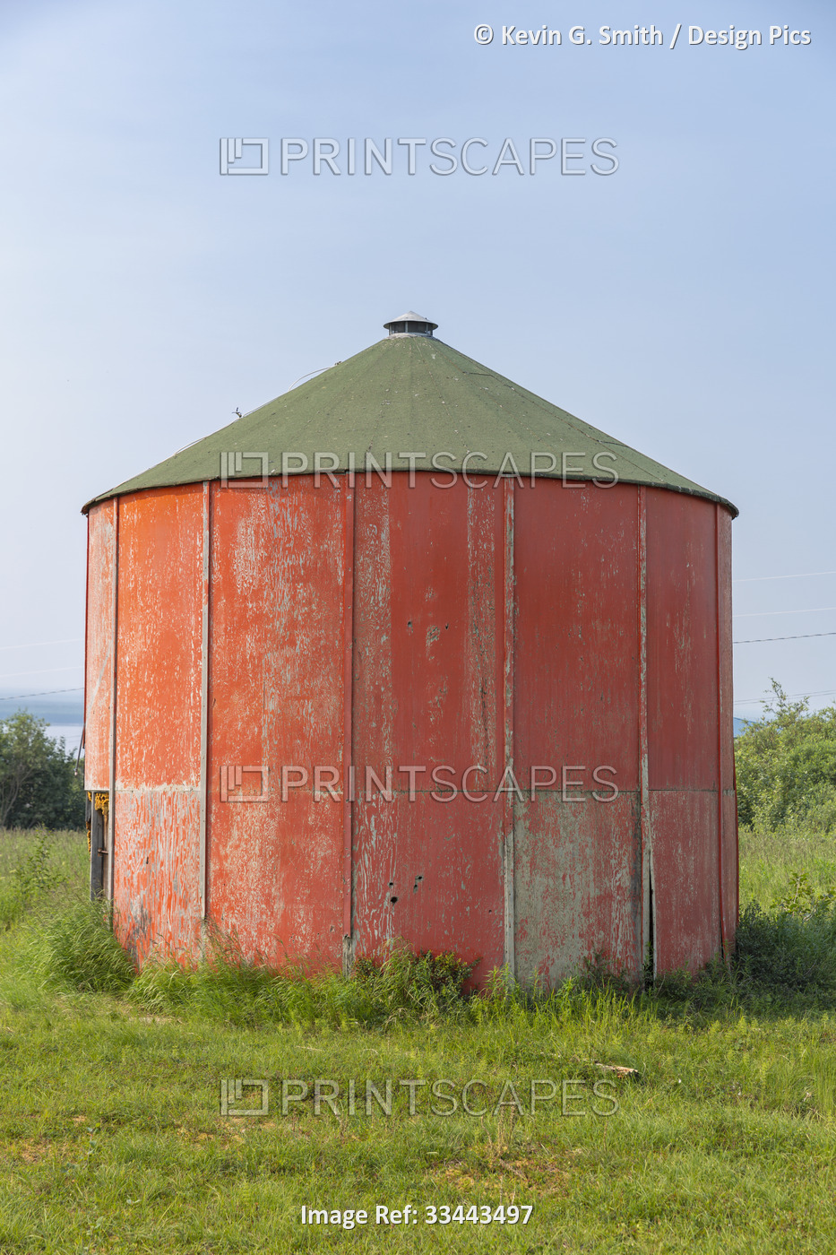 A weathered plywood sided, water storage tank is painted orange in Summer; ...