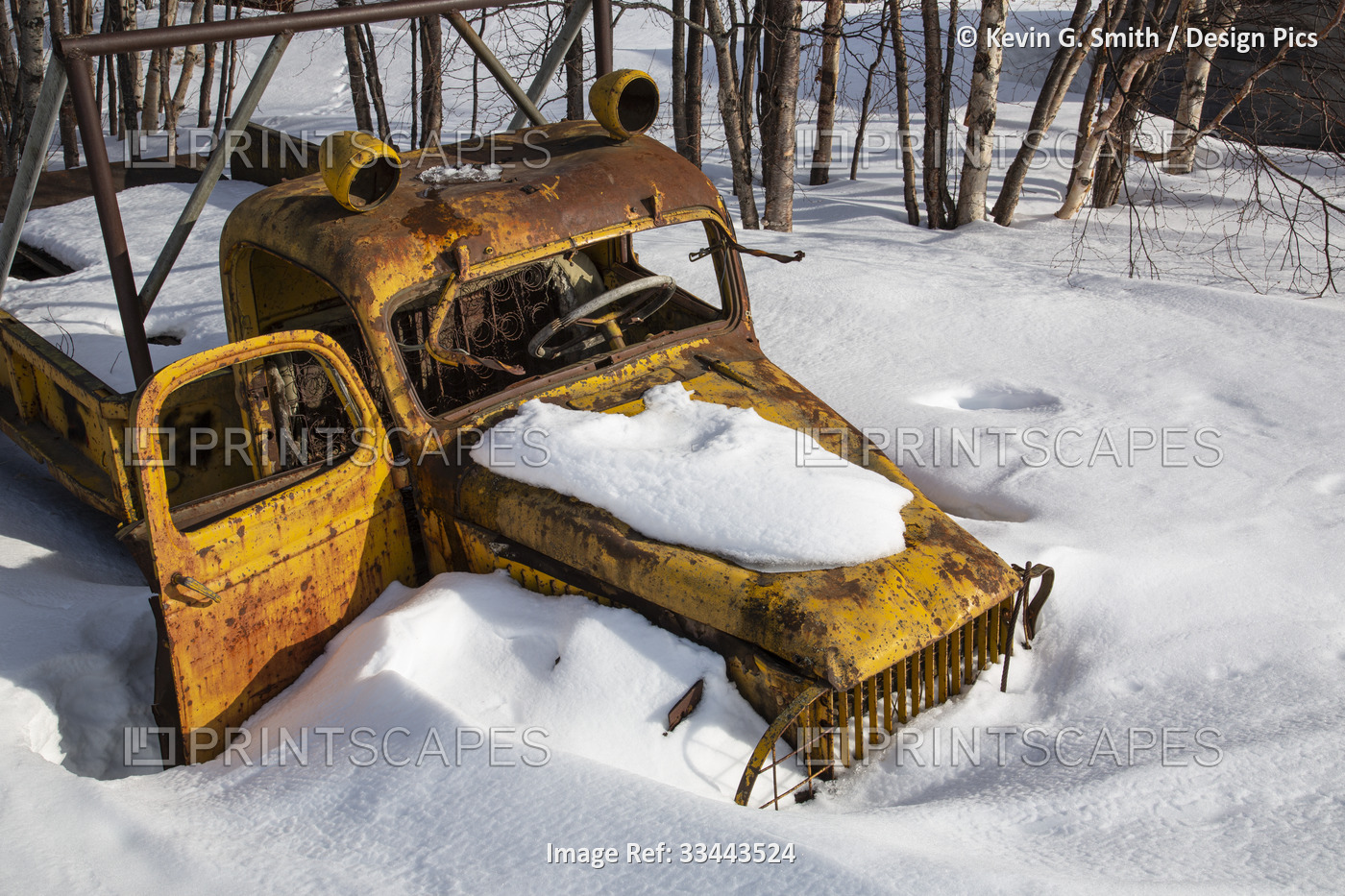Rusted vintage yellow flat bed truck surrounded by snow in winter, Kuskokwim ...
