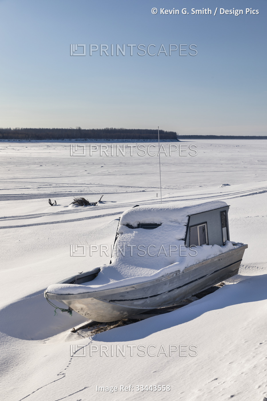 A fishing boat sitting in the snow, pulled up on the shore of the Yukon River ...