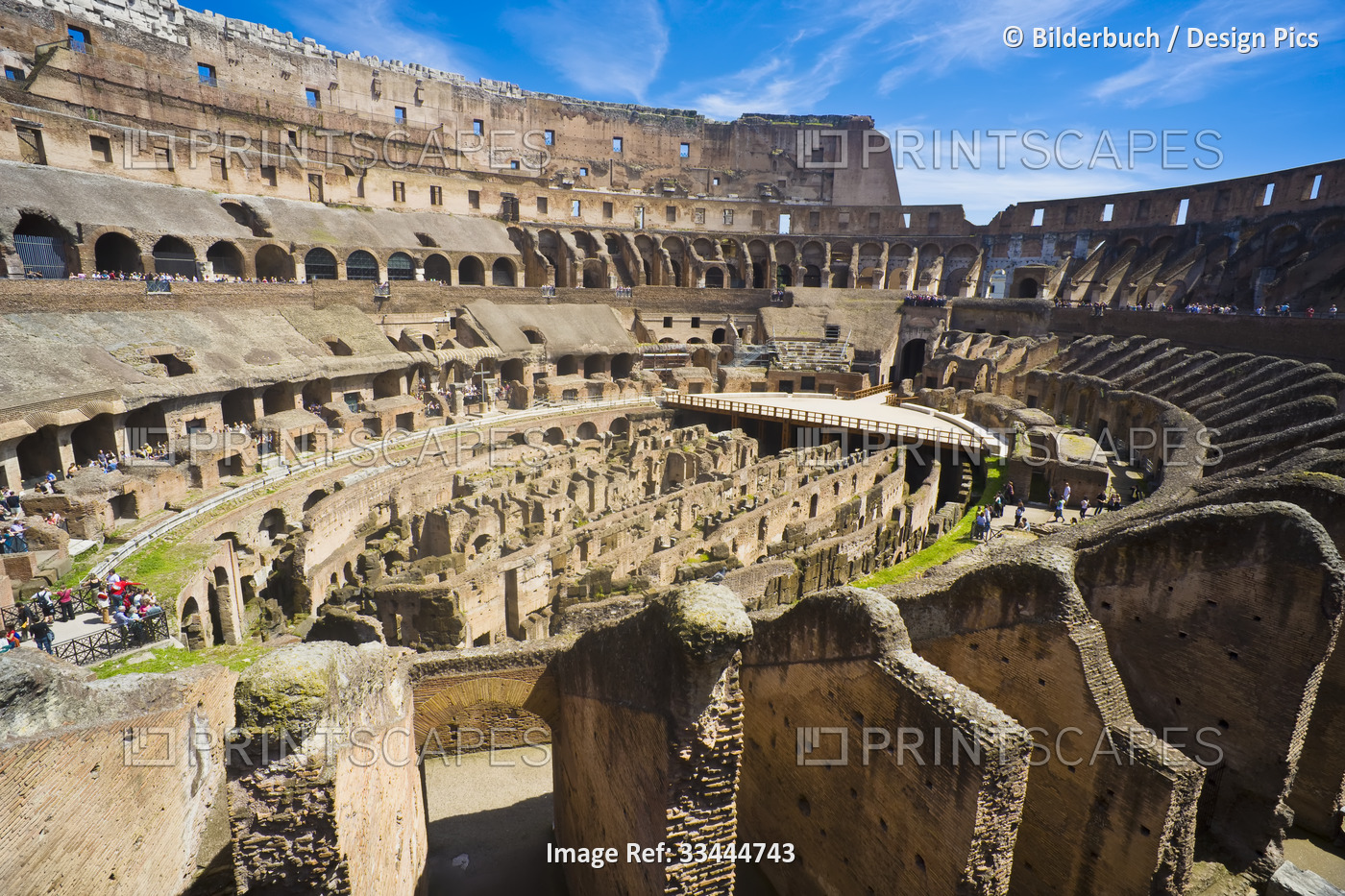 Overview of the interior of the iconic Colosseum against a blue sky with crowds ...