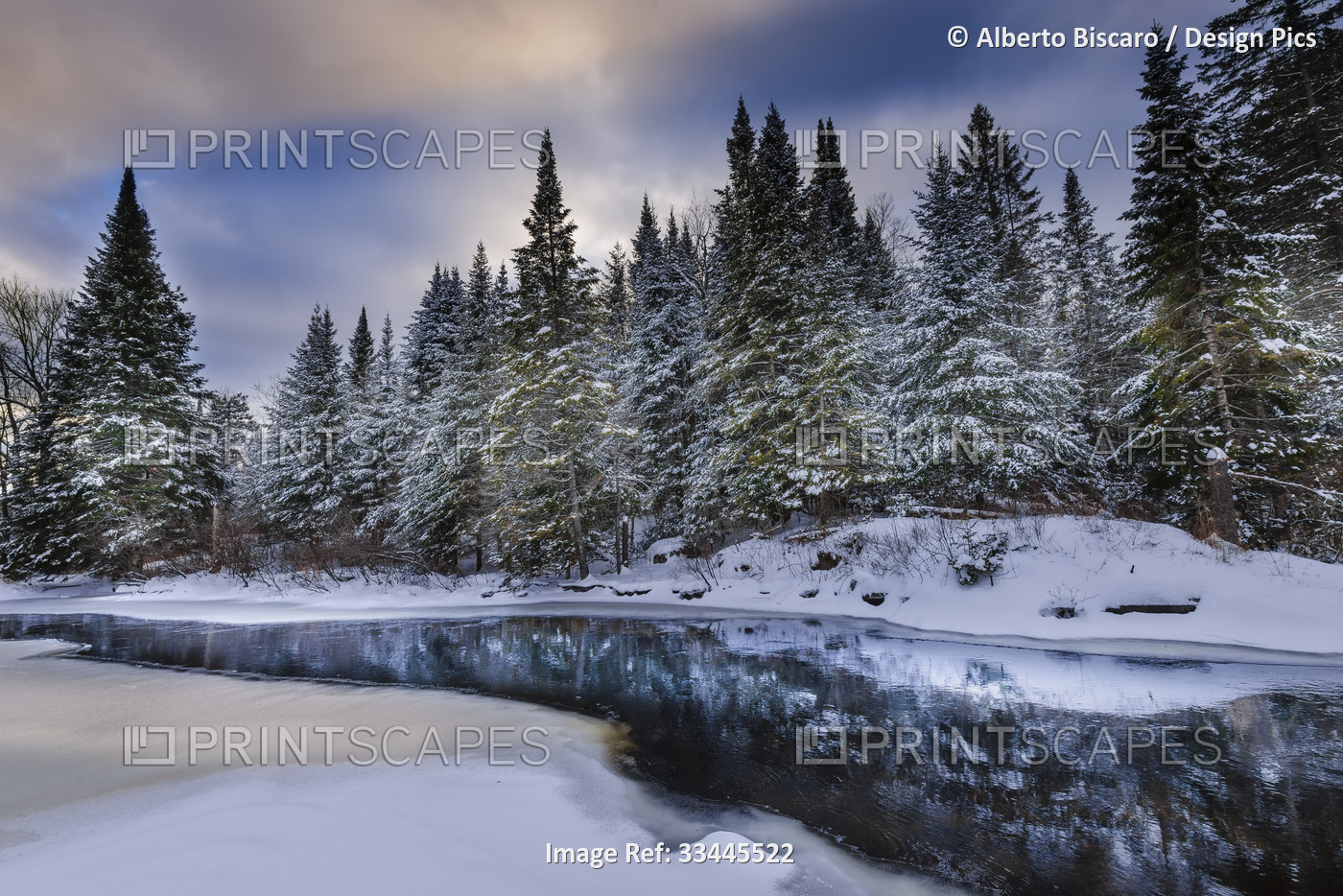 Tranquil winter landscape with reflections in water and drifting snow, ...