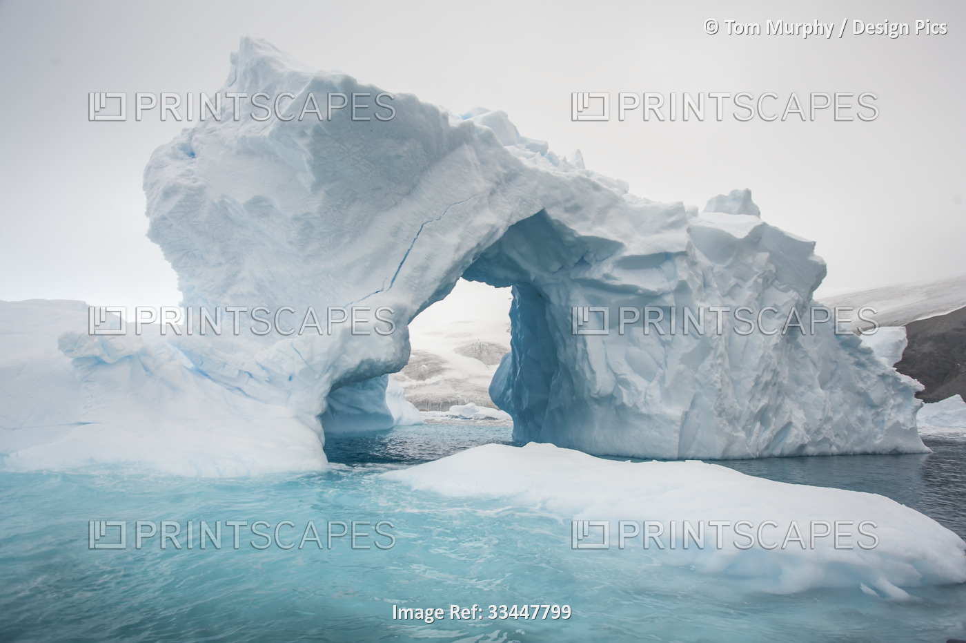 Abstract shape of an arched shaped iceberg with blue ice shadows and turquoise ...
