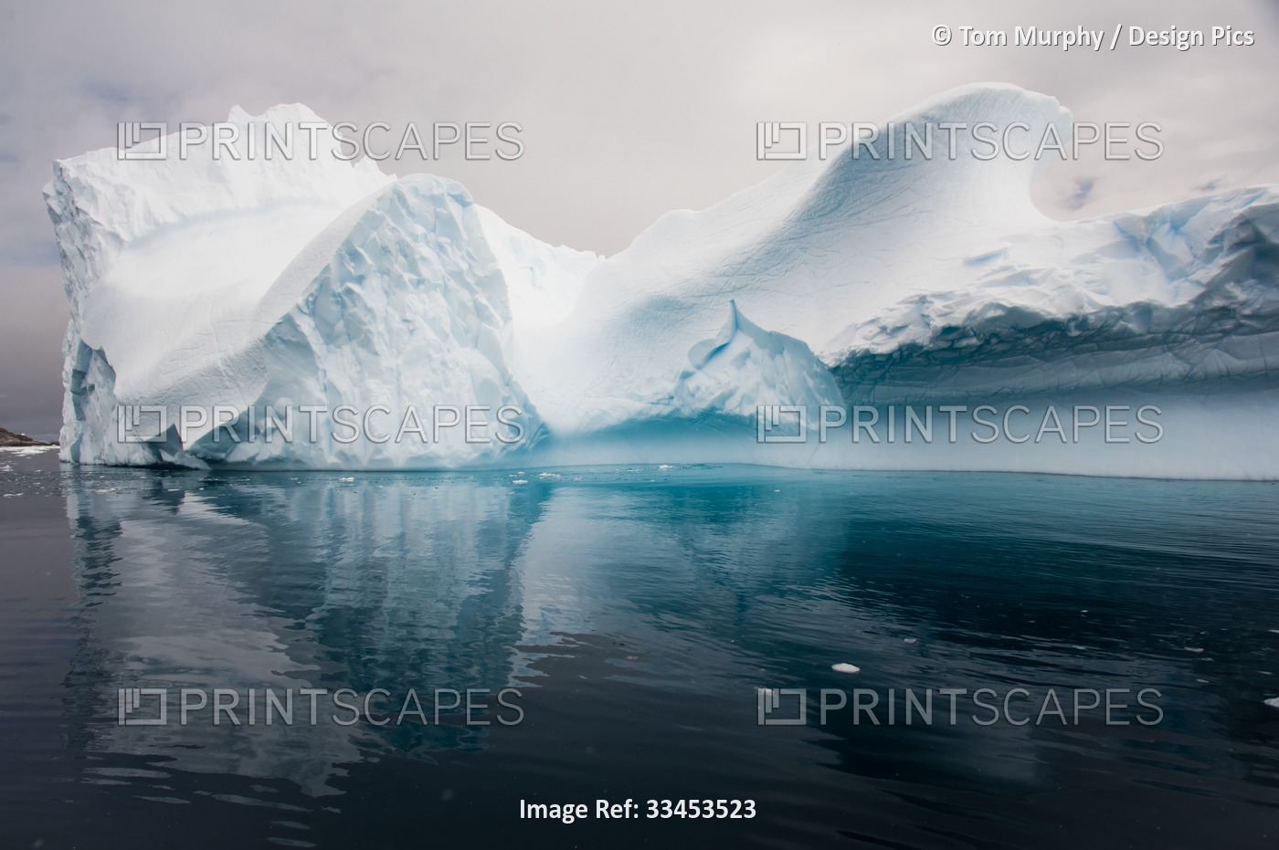 Abstract shape of an iceberg with blue ice shadows and dark, turquoise water of ...