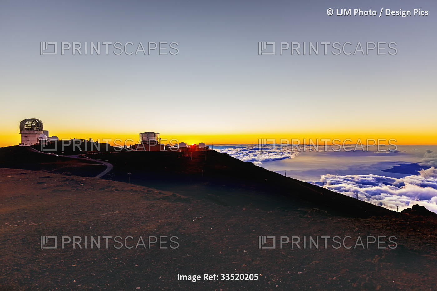 Haleakala Observatory buildings above the clouds with a golden sunset and a ...