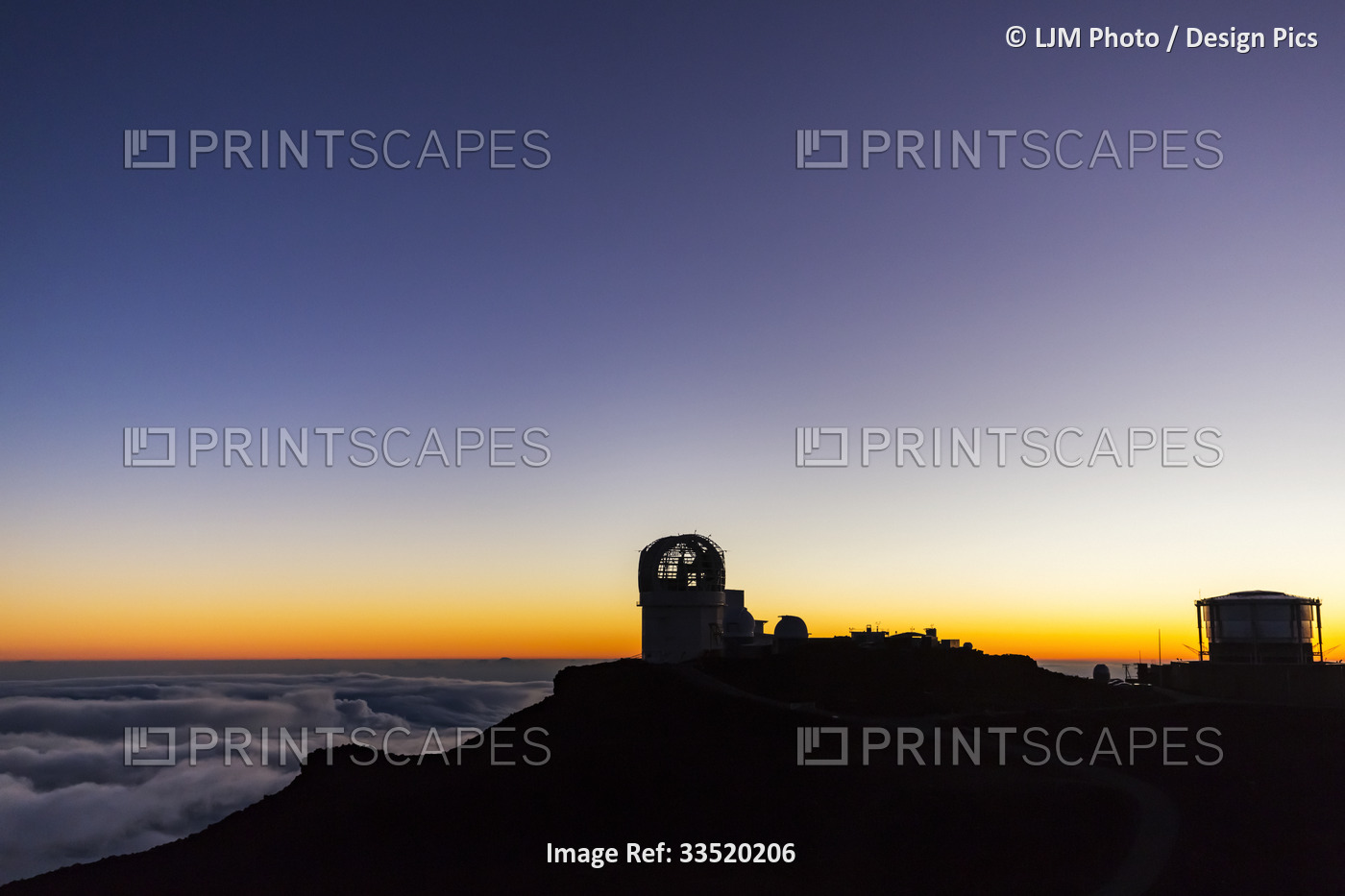 Haleakala Observatory buildings above the clouds along the top of a silhouetted ...
