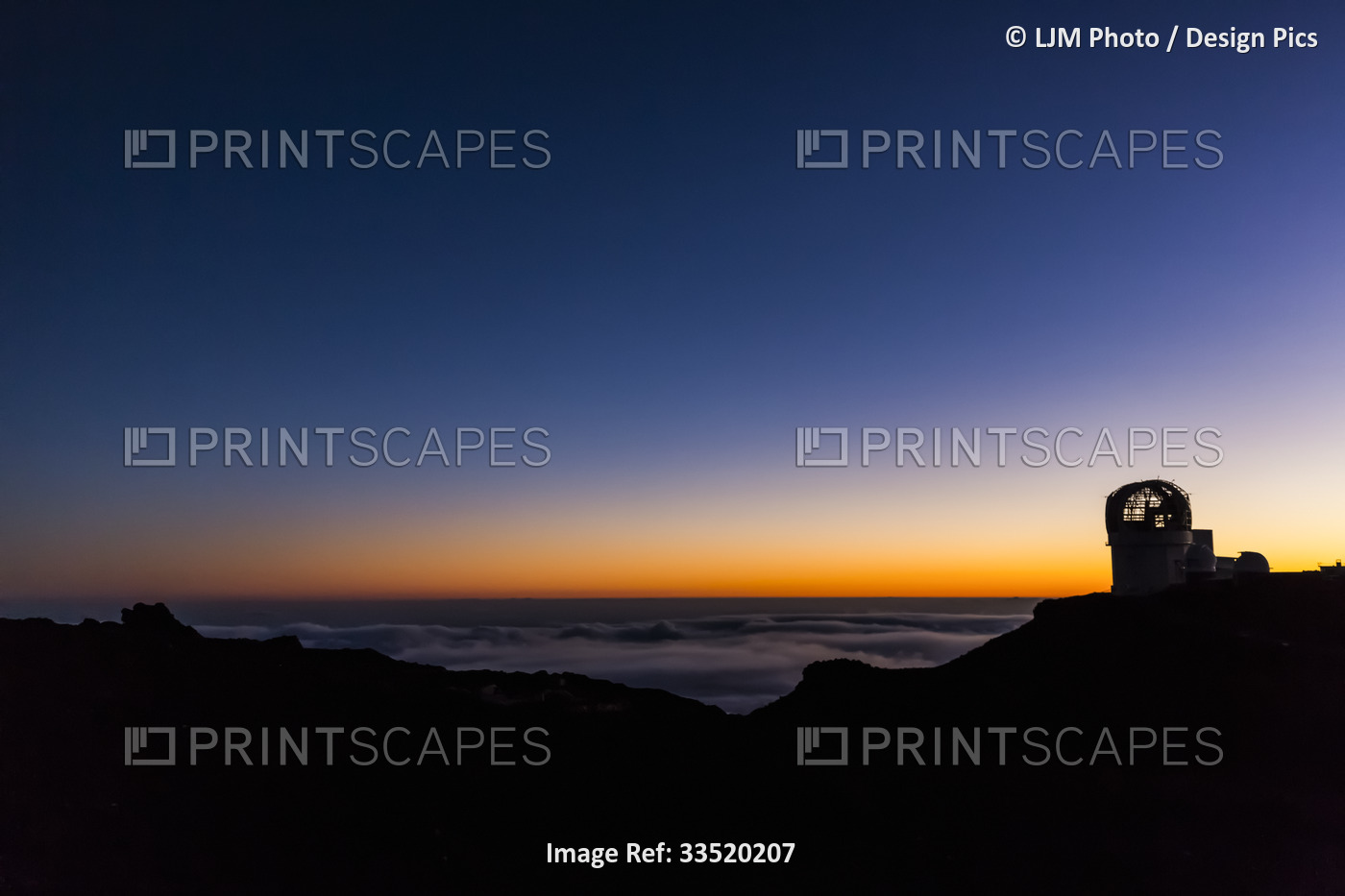 Haleakala Observatory buildings above the clouds along the top of a silhouetted ...