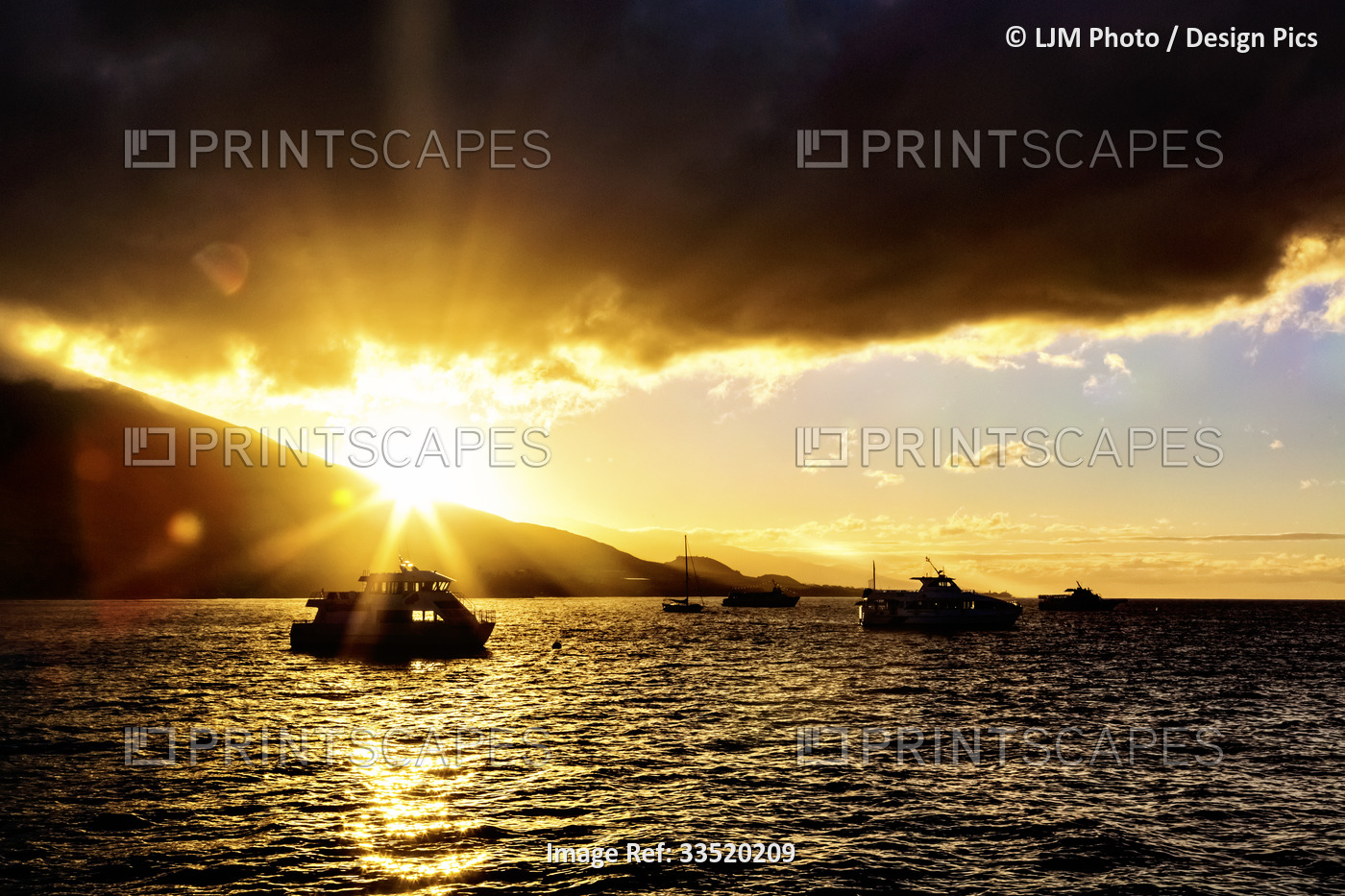 A golden sunset highlights the storm clouds above the silhouetted yachts moored ...