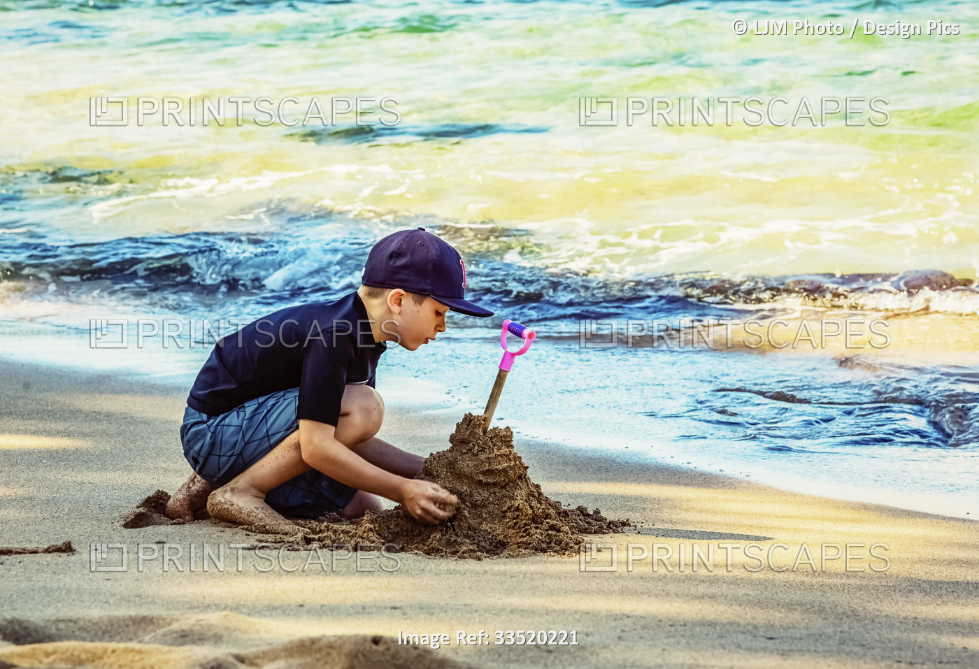 A young boy playing in the sand on the water's edge on the beach on Kapalua ...