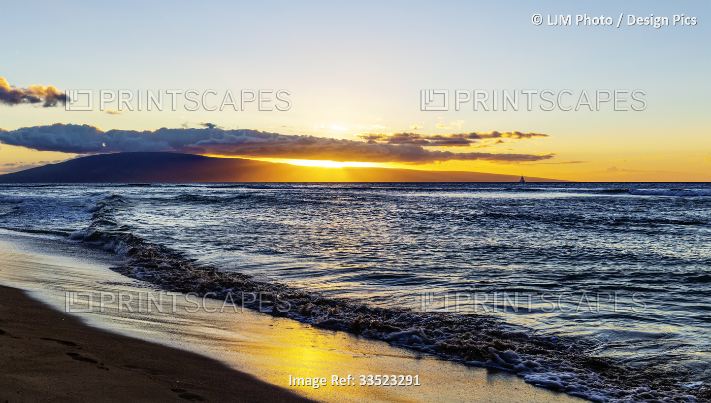 The tide rolls into a sandy beach at sunset along the Ka'anapali coast of West ...