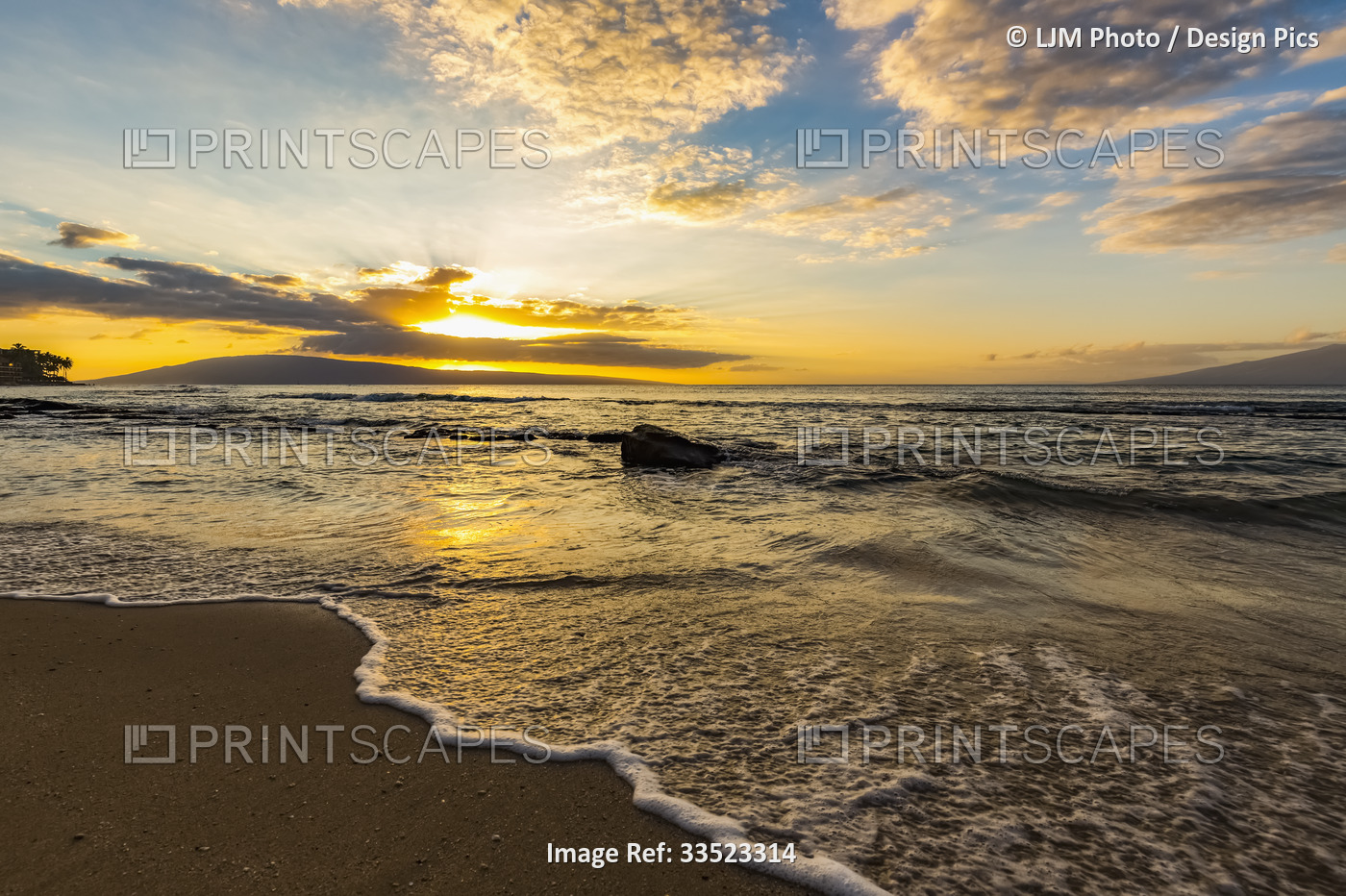 View from Ka'anapali Beach of the golden light over the ocean at sunset with ...