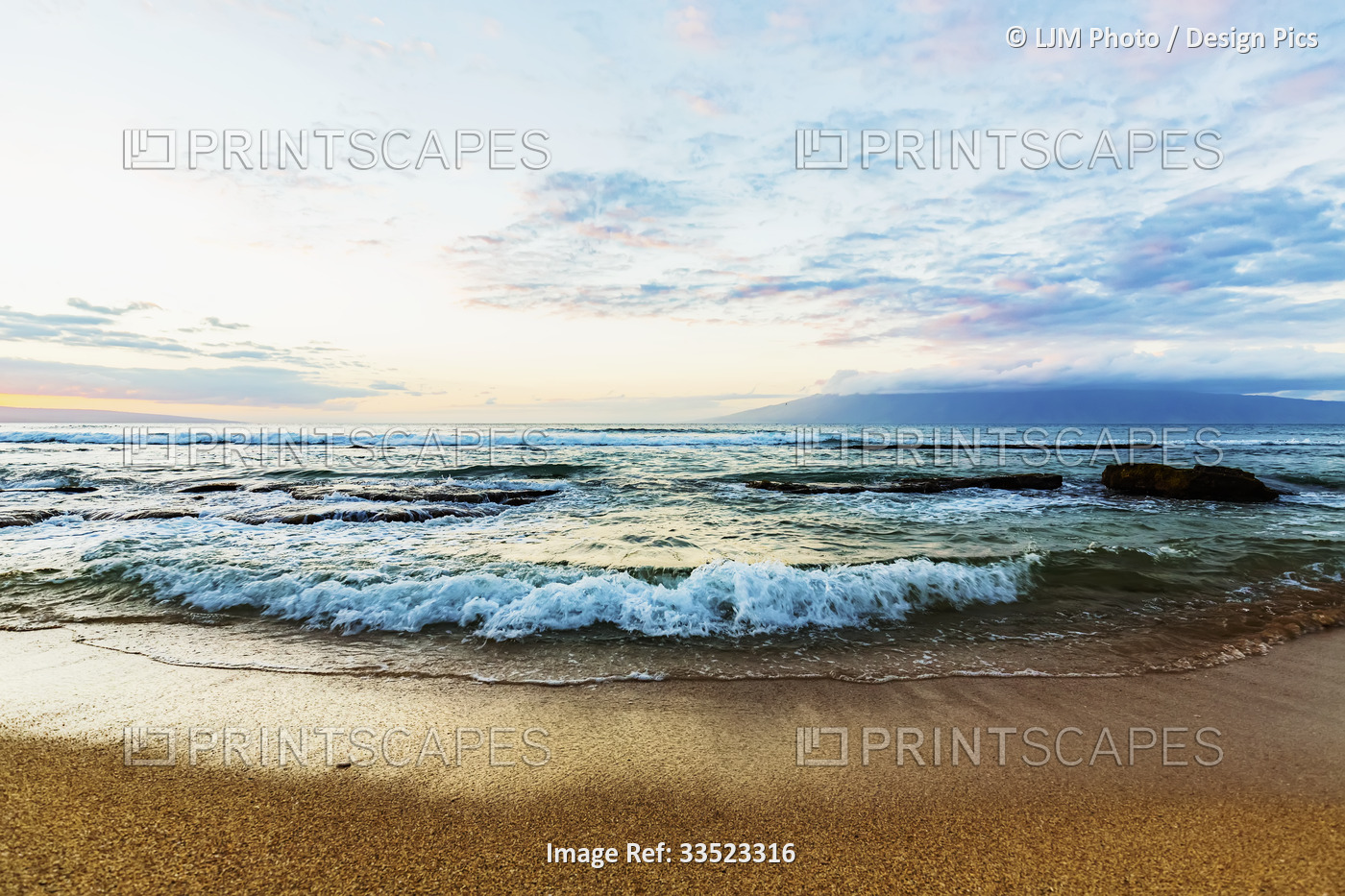 Ocean waves rolling over the large rocks at Ka'anapali Beach at sunset with the ...