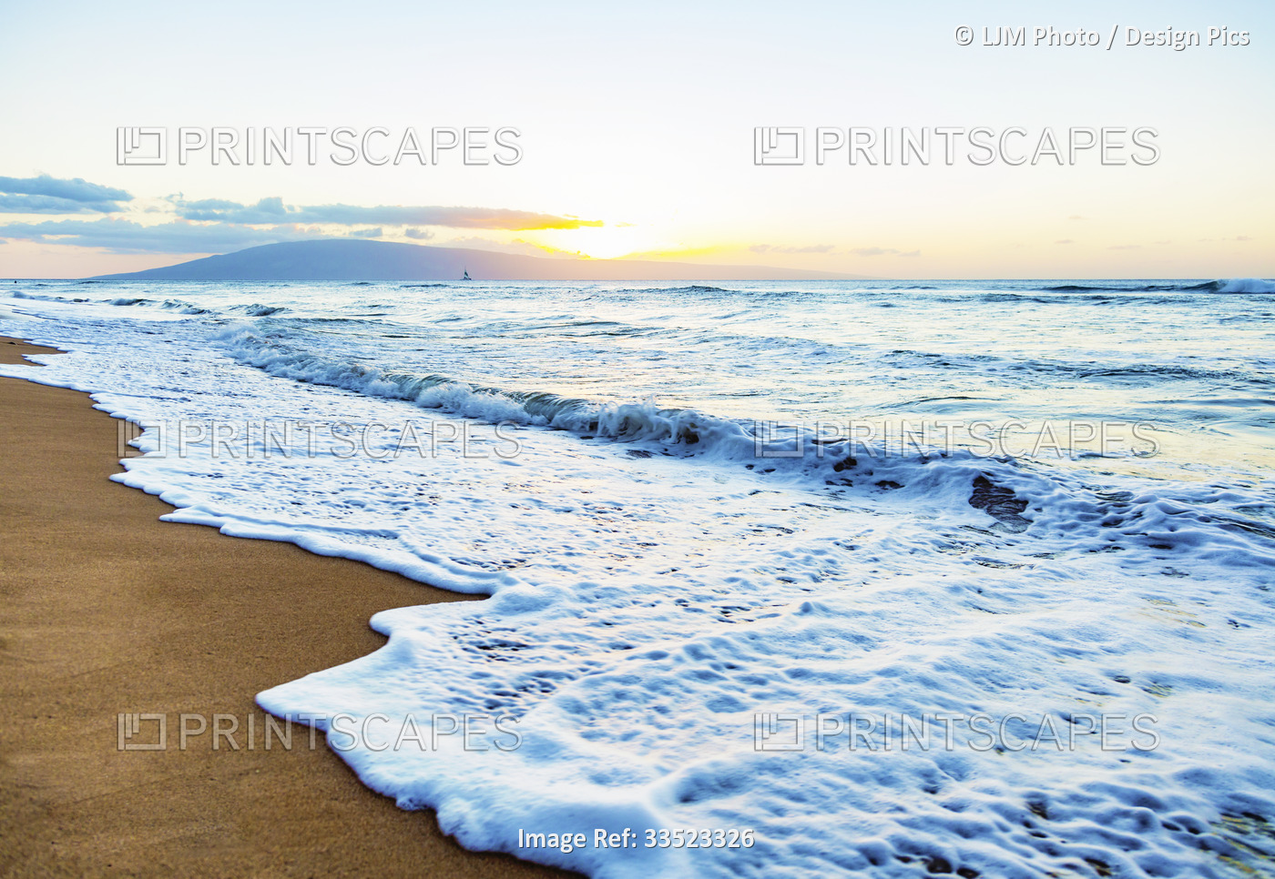 The sea surf foams as it rolls onto a beach with a view of the Island of Lanai ...