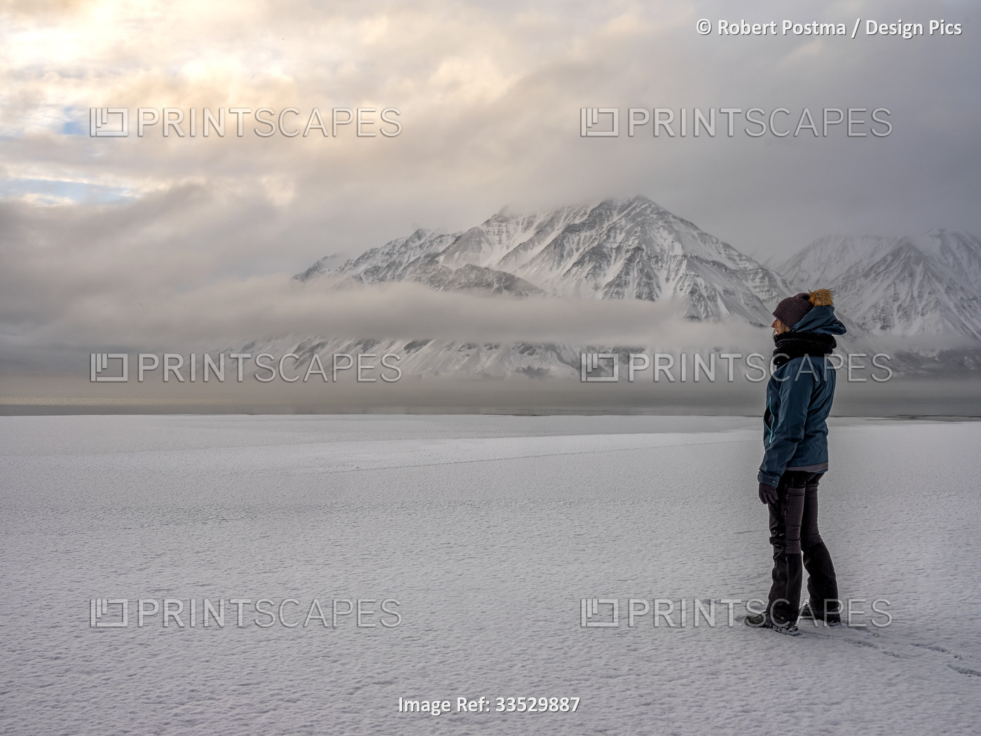 Woman standing on the frozen shoreline of Kathleen Lake looking out at the ...