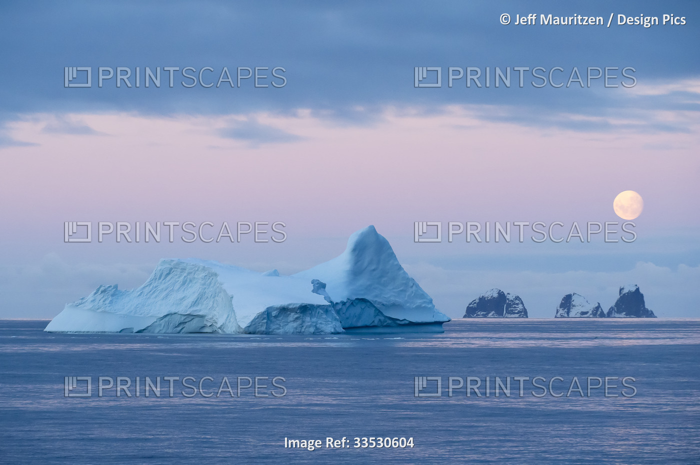 Full moon sets over icebergs and mountainous islands in the Gerlache Strait off ...