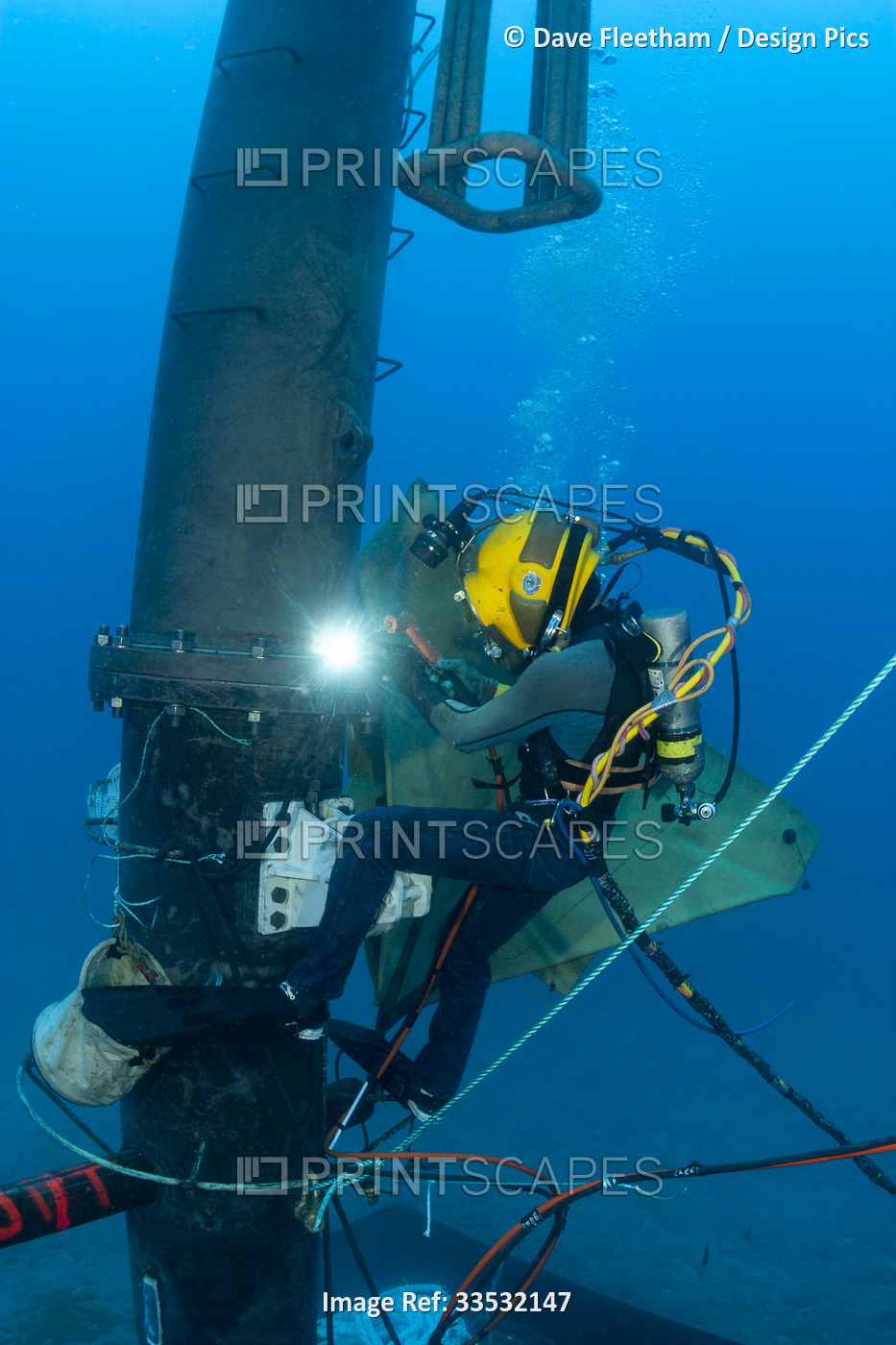 A commercial hard hat diver welding a fitting on a section of a wave energy ...