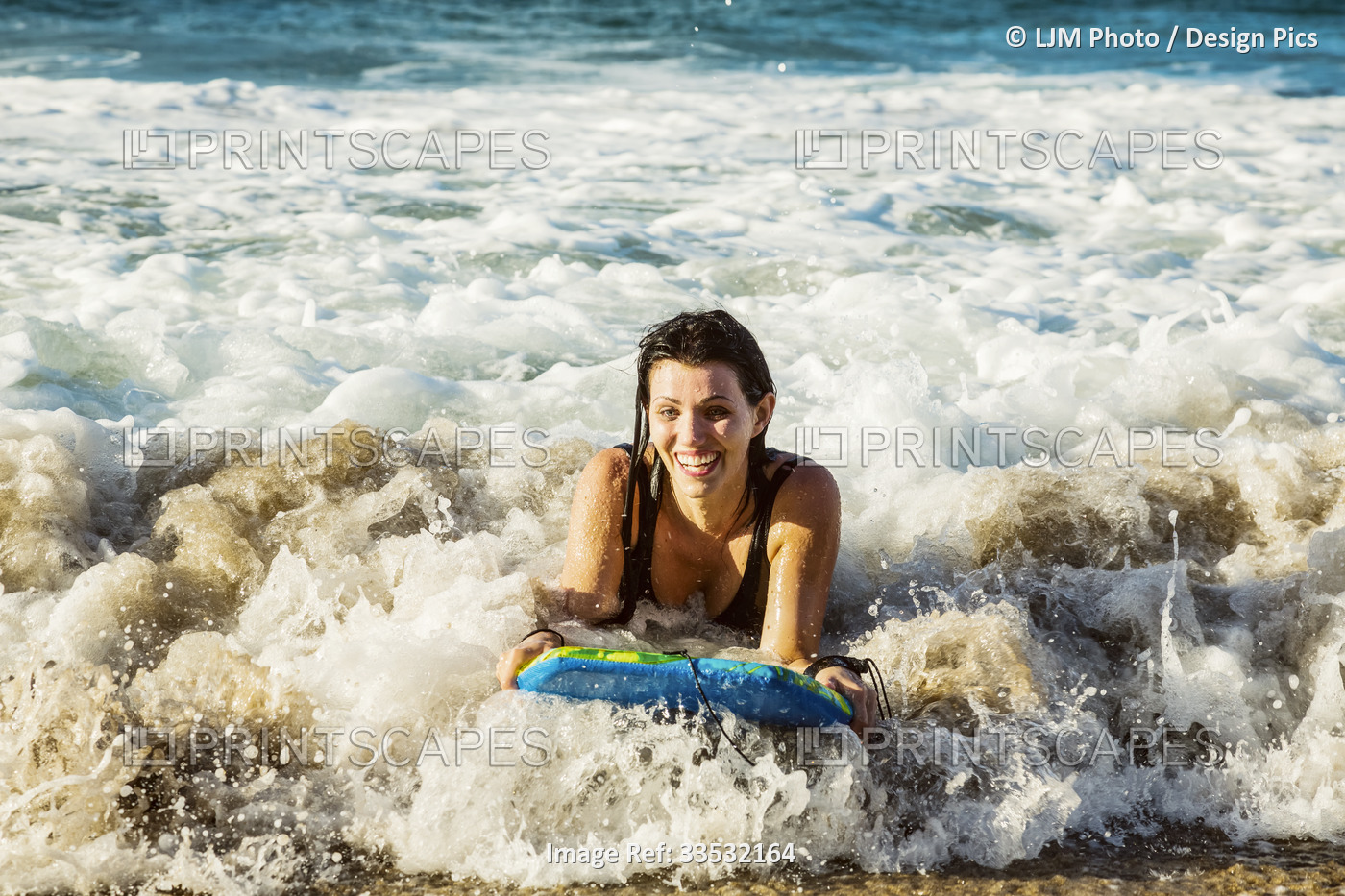 Close-up of a woman riding a wave on a bodyboard into the shore at D. T. ...