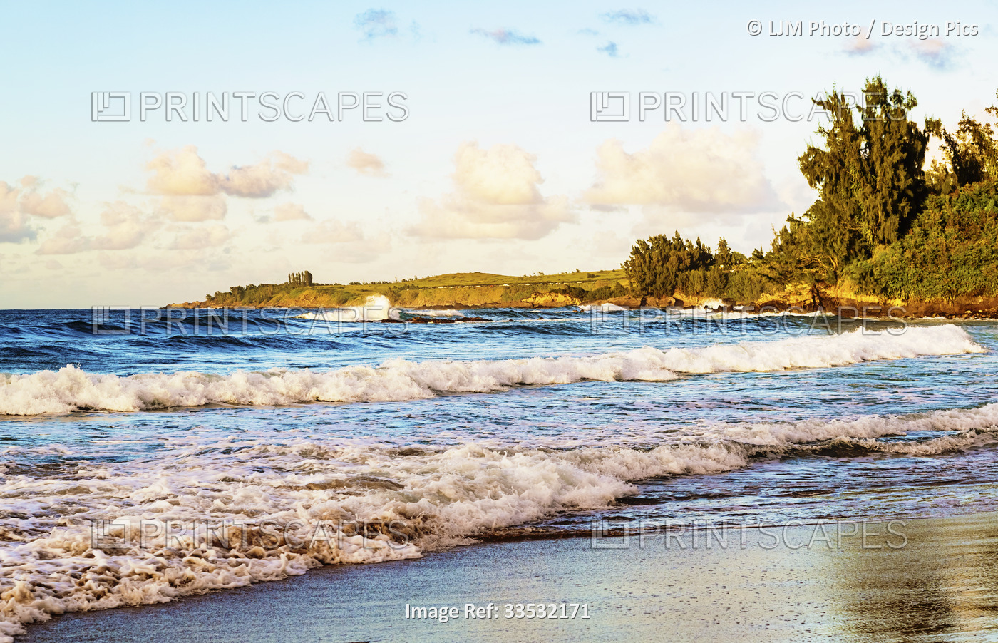 Waves roll into the beach with a view of the coastline at sunset on D.T. ...