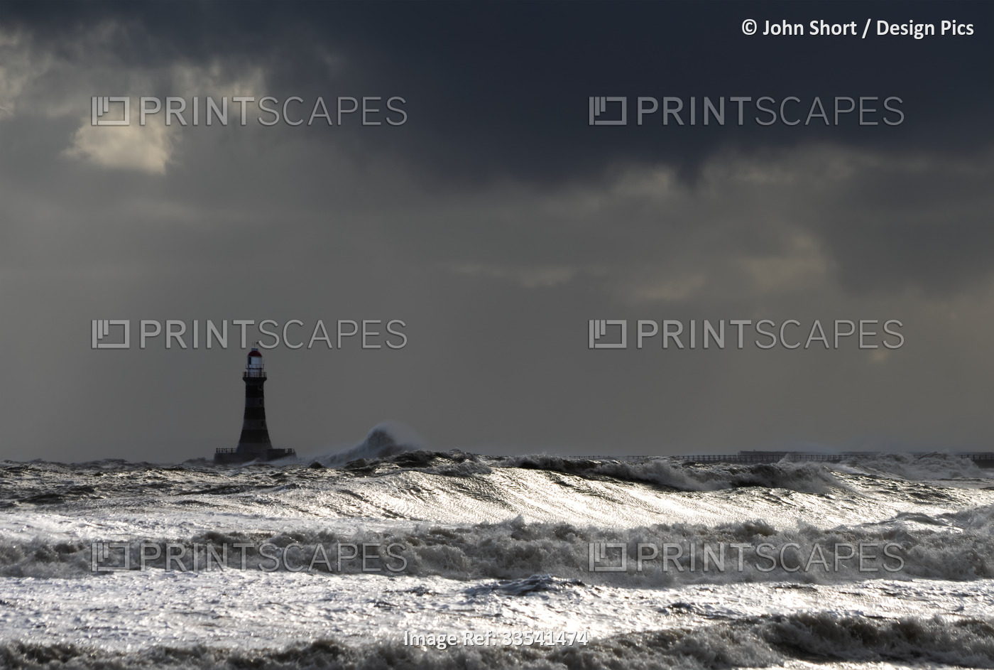 Roker Lighthouse and stormy waters splashing in the foreground; Sunderland, ...